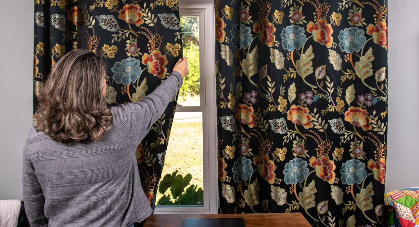 woman closing curtains